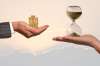 Foto: Hand mit Münzen und Hand mit Sanduhr